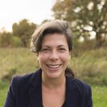 A photo of Amanda Lightner wearing a blue suit jacket standing in front of field of grass